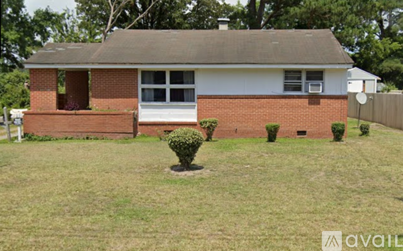 A house with a white front and a brown roof with a small garden in front.