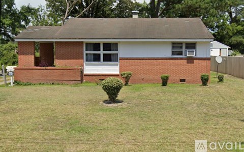 A house with a white front and a brown roof with a small garden in front.