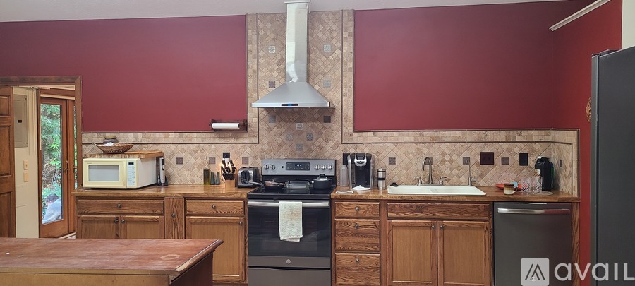 A kitchen with a red wall and wooden cabinets.