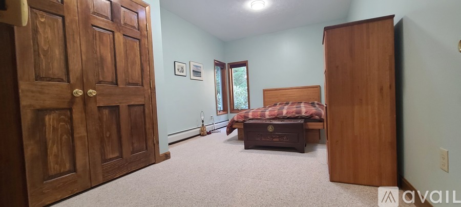 A bedroom with a bed, dresser, and wardrobe.
