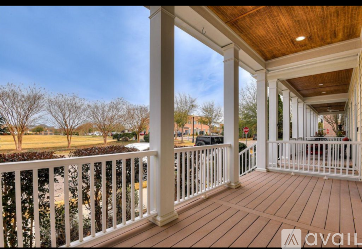 A porch with a white railing and a wooden floor.
