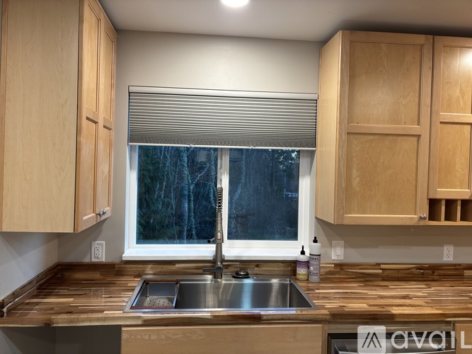 A kitchen with wooden cabinets and a window with blinds.