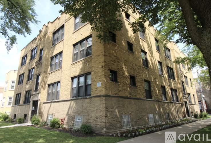 A tall brick building with many windows is surrounded by trees.