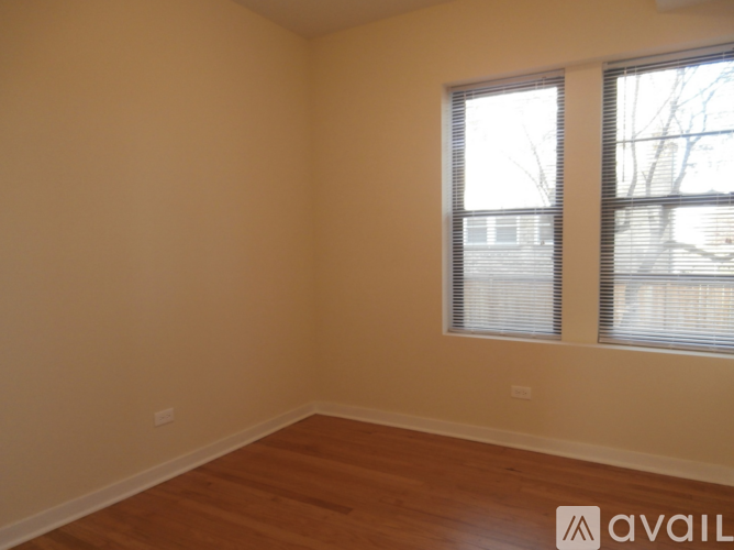 A spacious room with wooden flooring and a large window.