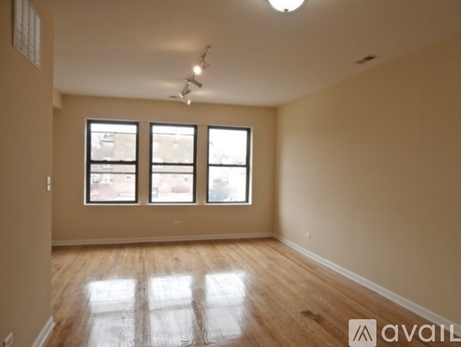 A room with wooden floors and three windows.