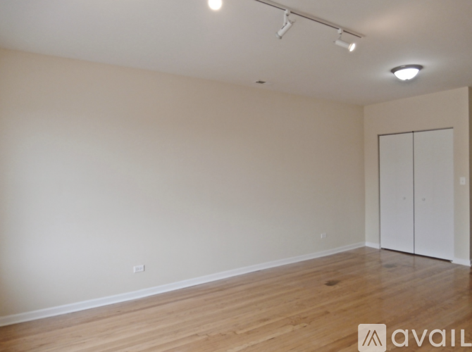 A room with wooden floors and white walls, with a white door and a light on the ceiling.