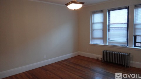 A room with wooden floors and a window with blinds.