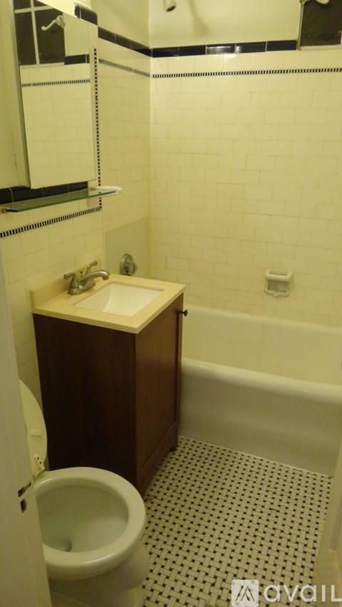 A white toilet is in a small bathroom with a sink and a bathtub.