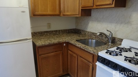 A kitchen with a white fridge, a white stove, and wooden cabinets.