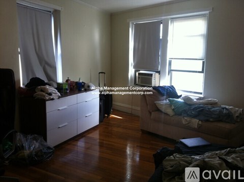 A messy room with a bed, dresser, and window.
