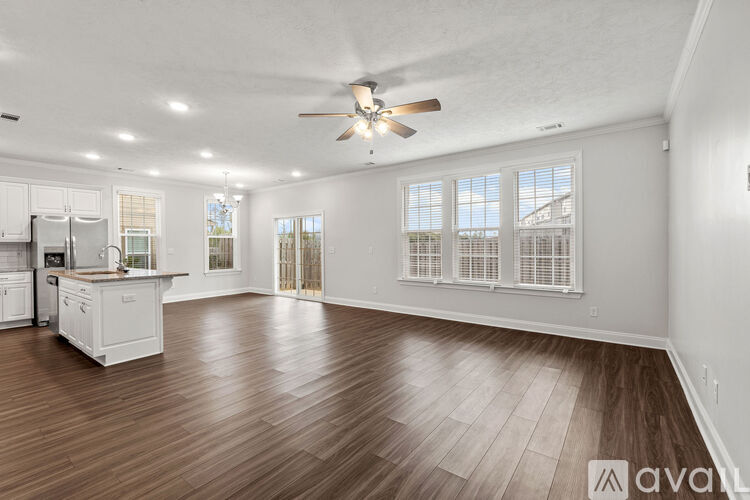 A spacious living room with hardwood floors and a ceiling fan.