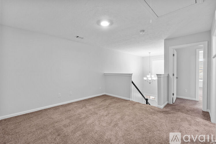 A spacious room with a carpeted floor and a staircase leading to another room.