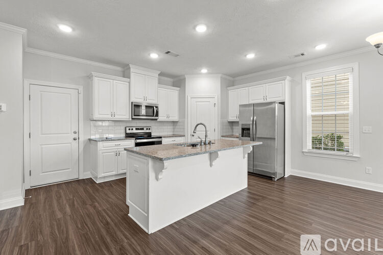 A kitchen with white cabinets and a wooden floor.