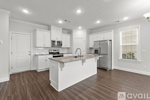 A kitchen with white cabinets and a wooden floor.