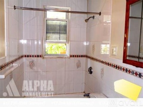 A bathroom with a shower, a window, and a mirror.