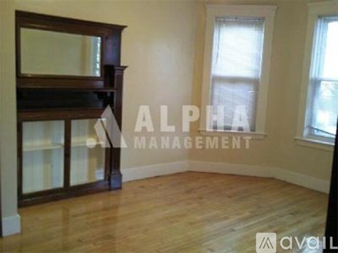 A room with wooden flooring and a large window with white blinds.