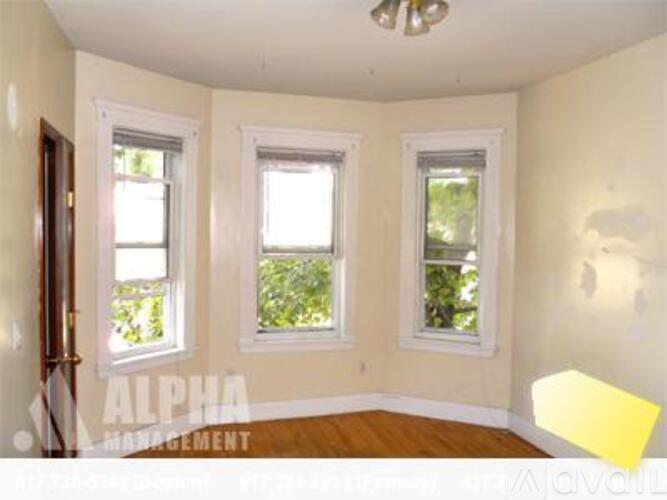 A room with three windows and a wooden floor.