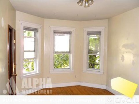 A room with three windows and a wooden floor.