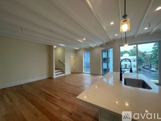 A spacious room with wooden floors and a large window overlooking a street.