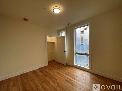 A room with wooden flooring and a window showing a city view.