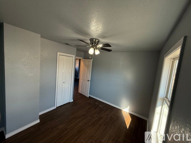 A room with a ceiling fan and wooden flooring.