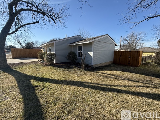 A house with a white exterior and a brown fence is shown in the image.