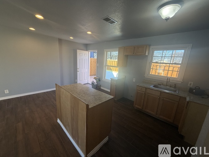 A room with a kitchen area and a wooden box in the middle.