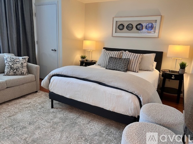 A bedroom with a large bed, a chair, and two lamps.