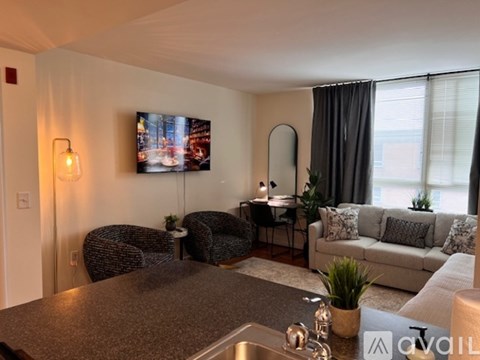 A living room with two chairs, a table, and a television displaying a snowy scene.