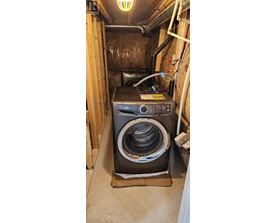 A black washing machine in a small, enclosed space.