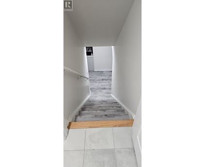 A hallway with a wooden floor and white walls.