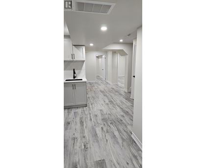 A kitchen with white cabinets and a wooden floor.