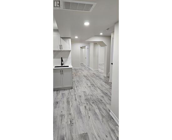 A kitchen with white cabinets and a wooden floor.