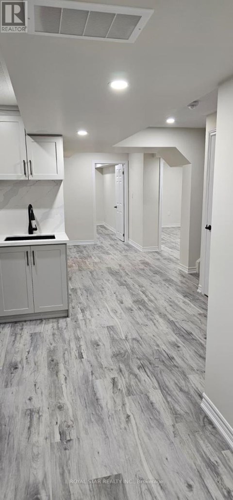 A kitchen with white cabinets and a wooden floor.
