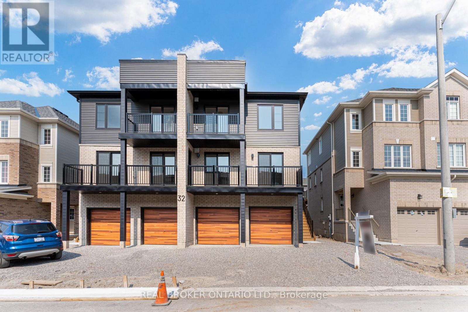 A modern two-story building with a balcony and garage doors.
