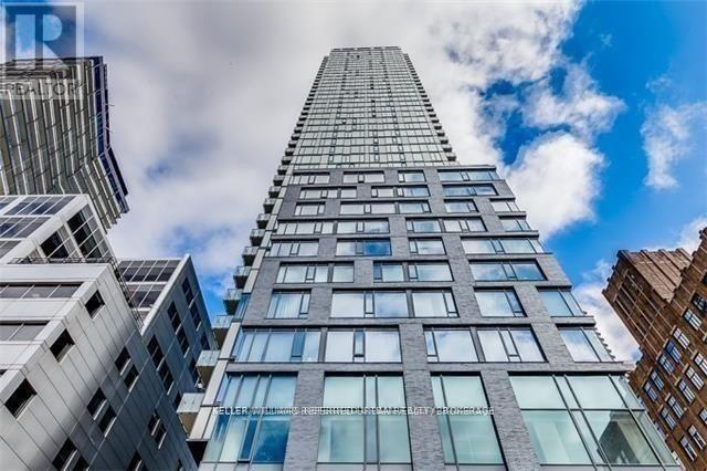 A tall building with many windows stands in front of other buildings.