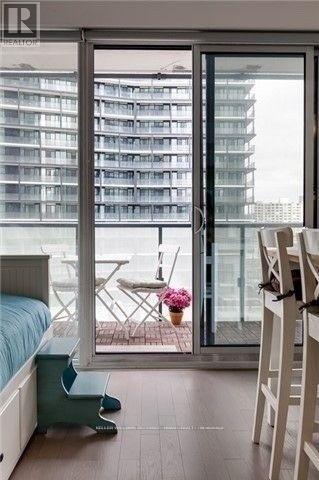 A bedroom with a bed, chair, and sliding glass doors.