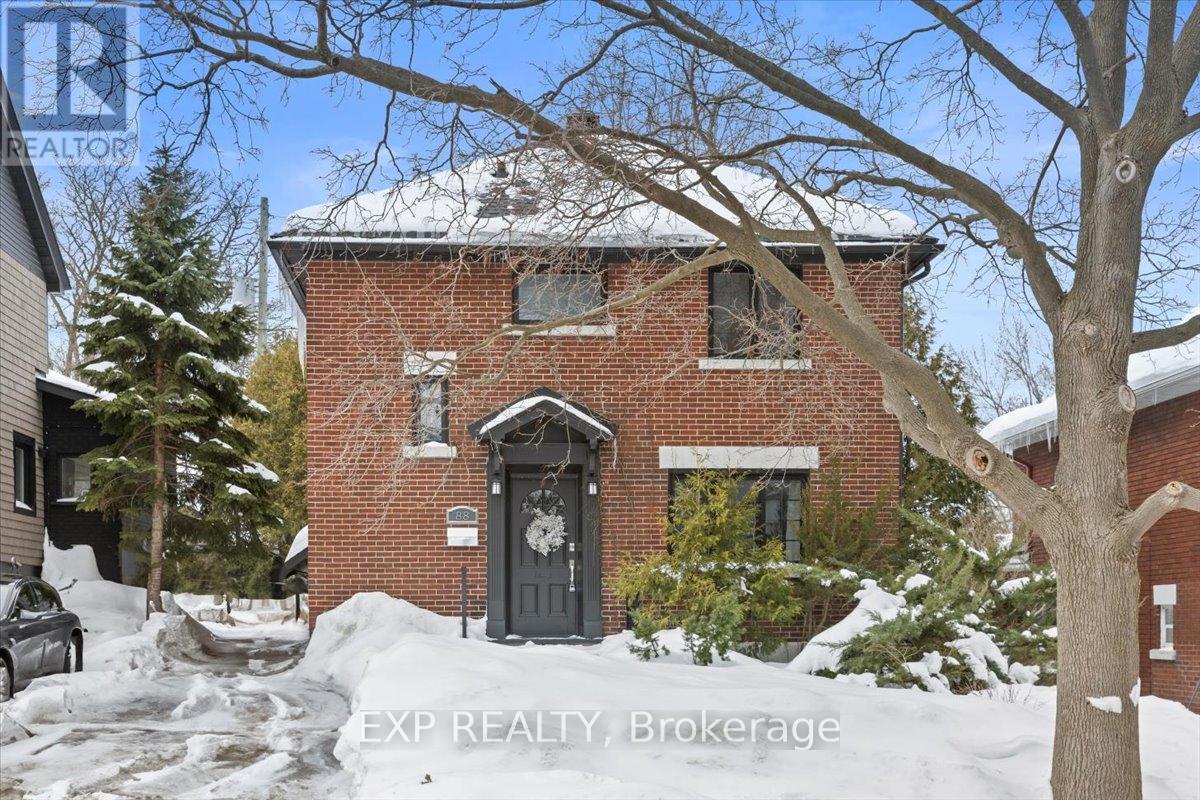 A red brick house with a black door and a sign that says EXP REALTY Brokerage.