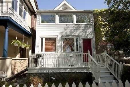 A white house with a red door and a white picket fence.