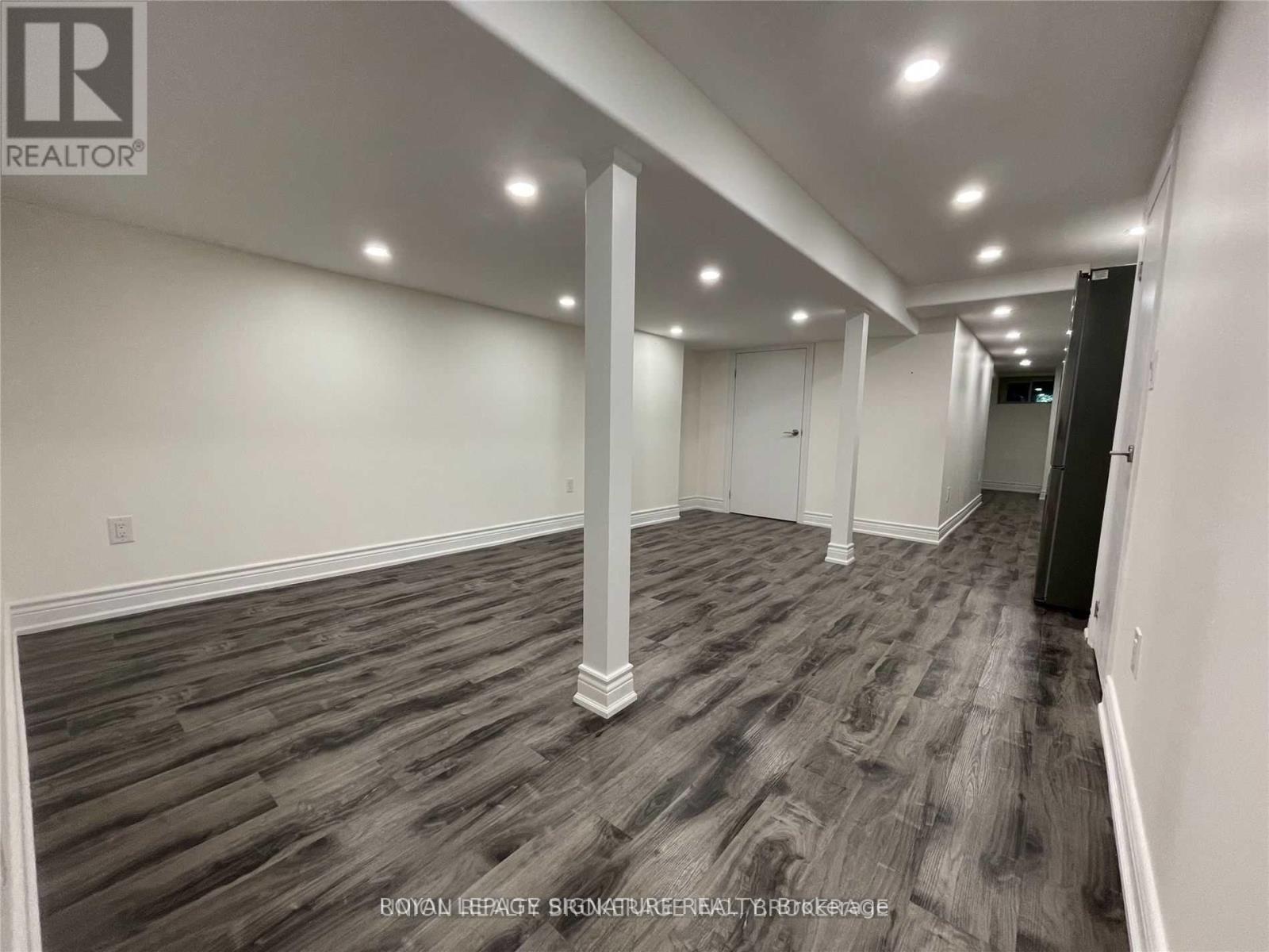 A spacious room with wooden flooring and white walls.