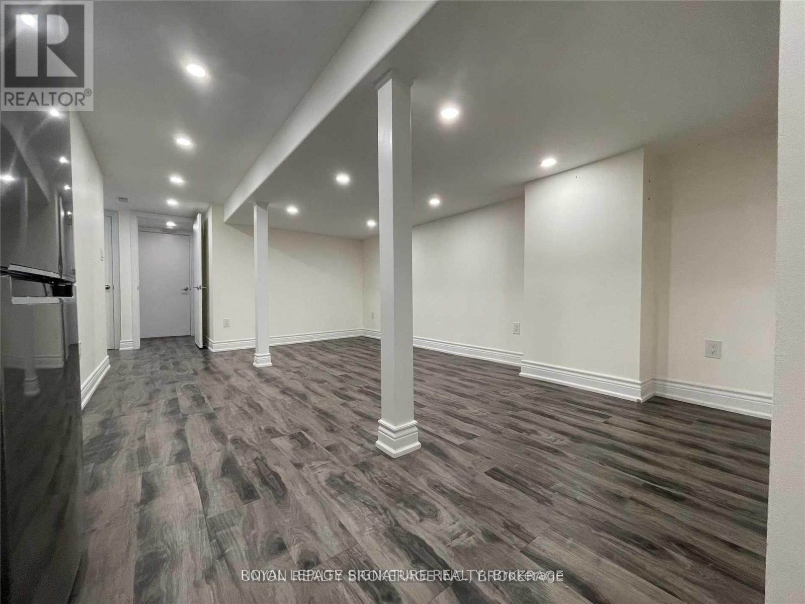 A spacious room with wooden flooring and white walls.
