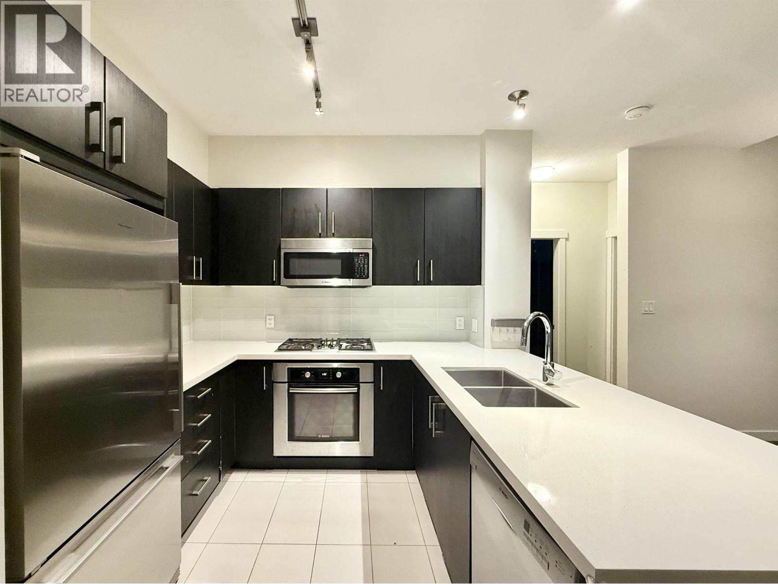 A modern kitchen with black cabinets and stainless steel appliances.