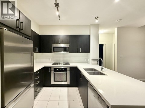 A modern kitchen with black cabinets and stainless steel appliances.