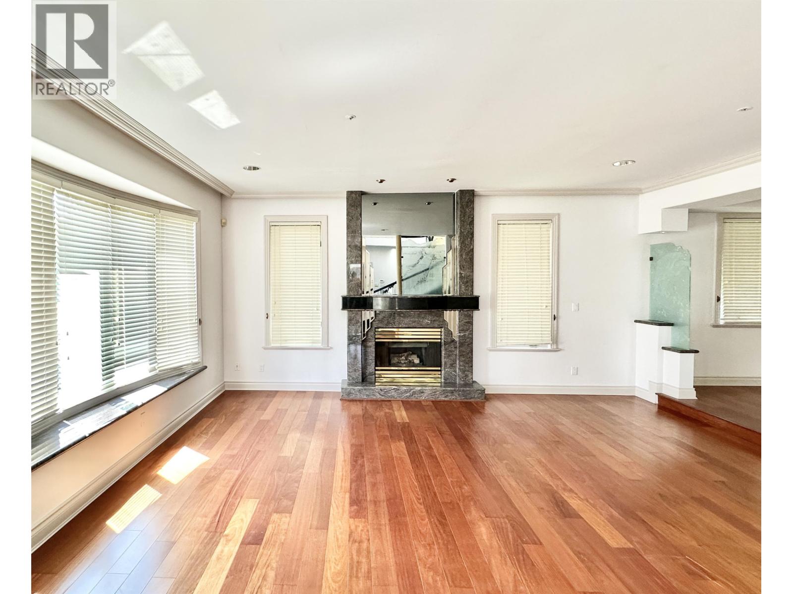 A large, empty room with wooden floors and a fireplace.