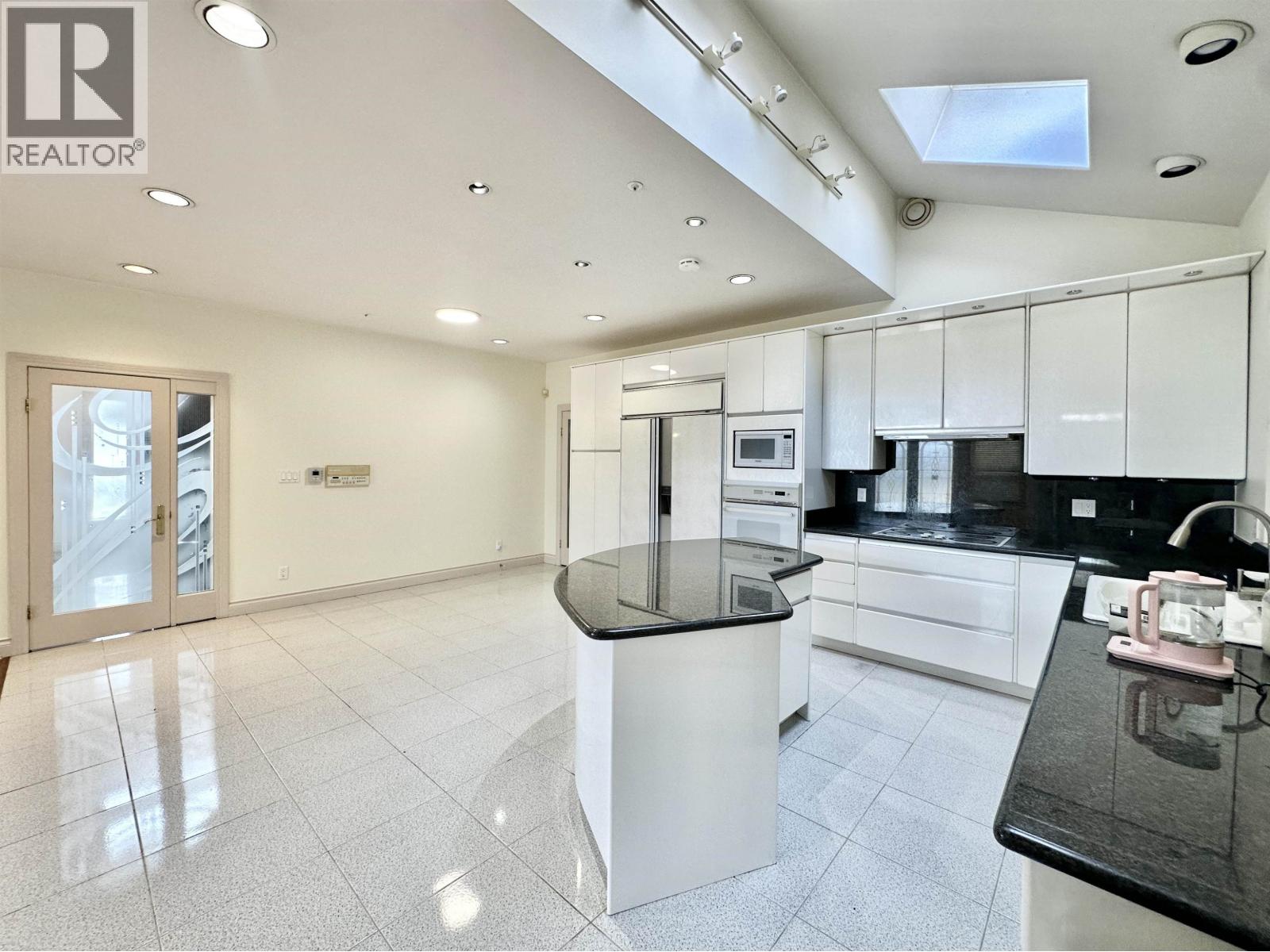 A modern kitchen with white cabinets and black countertops.