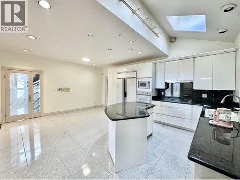 A modern kitchen with white cabinets and black countertops.