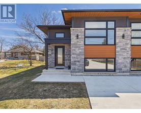 A modern house with a black and brown exterior is shown in the snow.