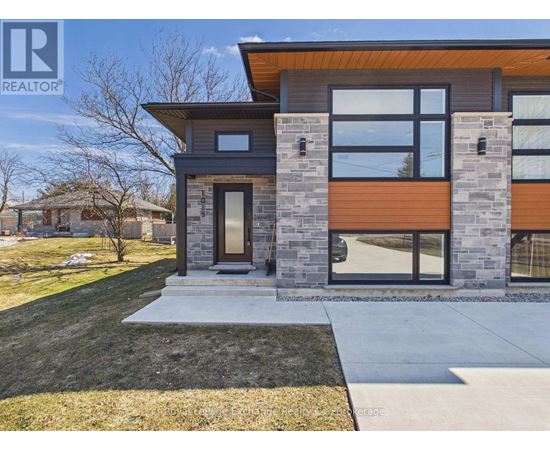 A modern house with a black and brown exterior is shown in the snow.