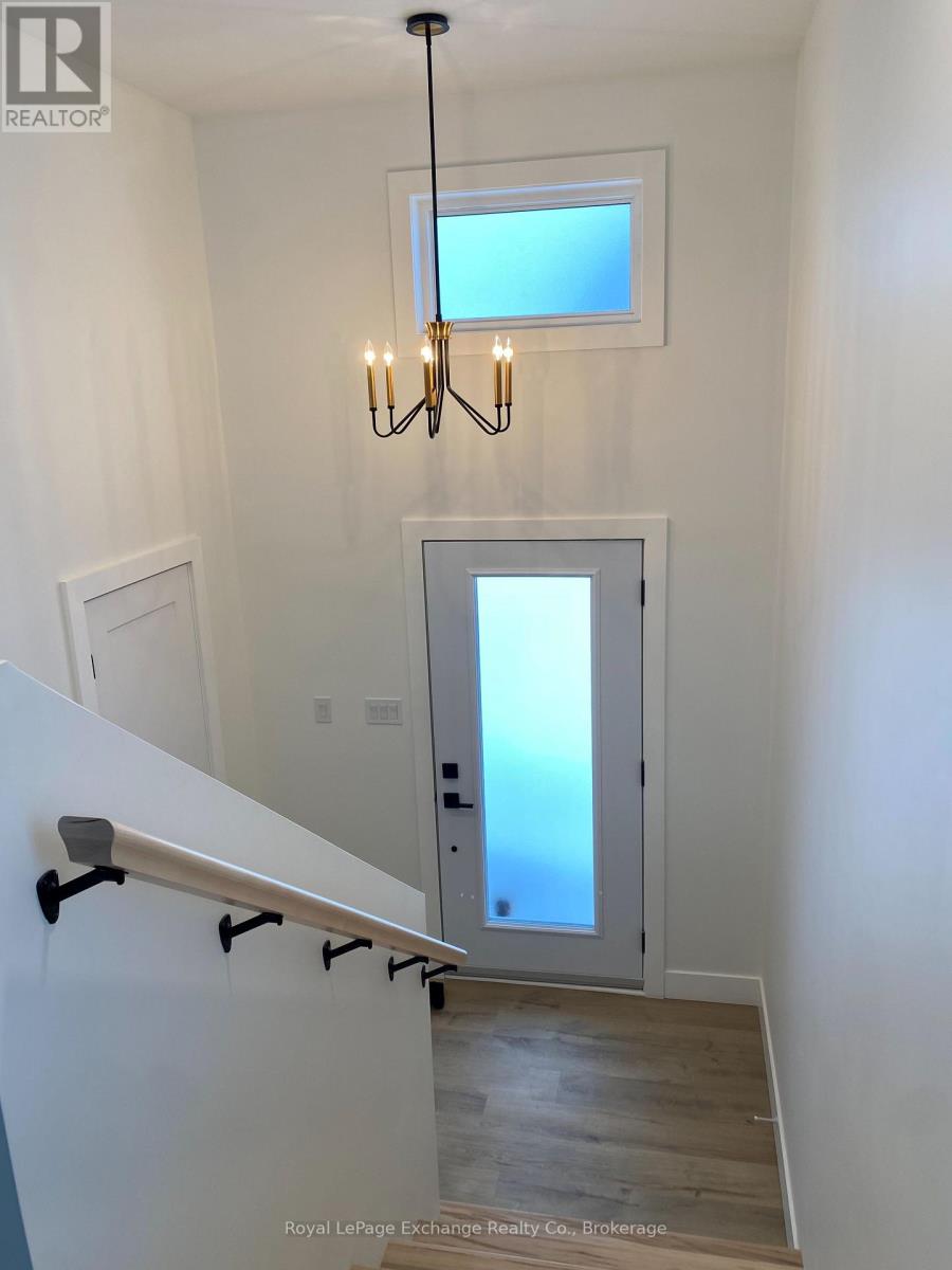 A chandelier hangs over a staircase with a glass door leading to a balcony.