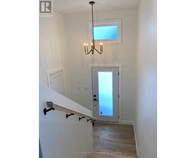 A chandelier hangs over a staircase with a glass door leading to a balcony.